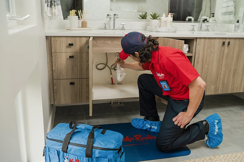 Mr. Rooter plumber repairing a bathroom sink drain pipe 