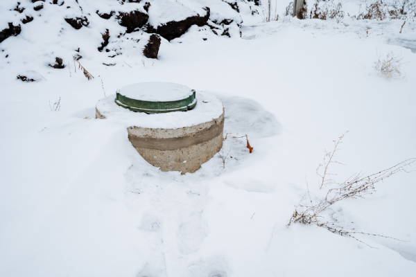 A septic tank is positioned right in the middle of a vast, snowcovered field, creating a striking contrast against the blanket of white that has gathered due to the winter season