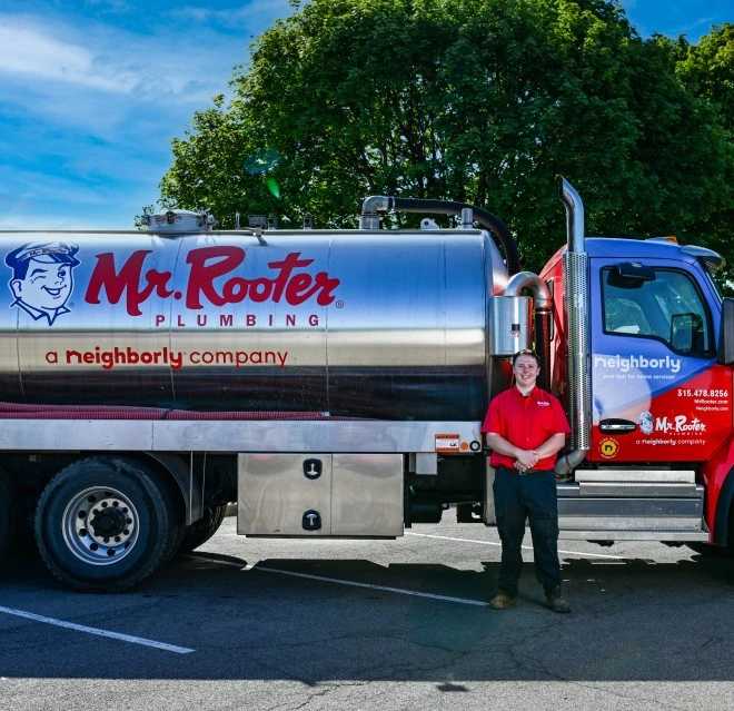 White Mr. Rooter truck parked with technician standing beside it.