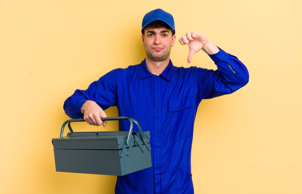 young man feeling cross,showing thumbs down. plumber concept