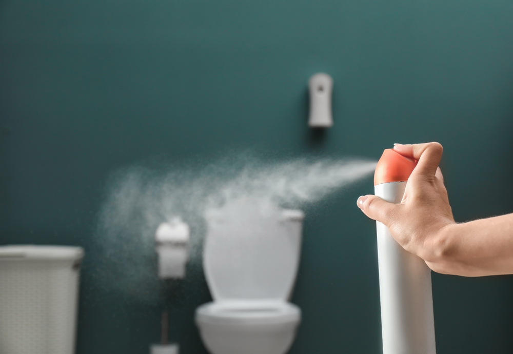 Woman spraying air freshener in bathroom