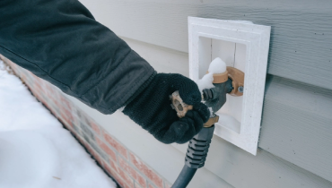 Individual checking an outdoor water valve on a cold and snowy day. | Mr. Rooter Plumbing of South Jersey