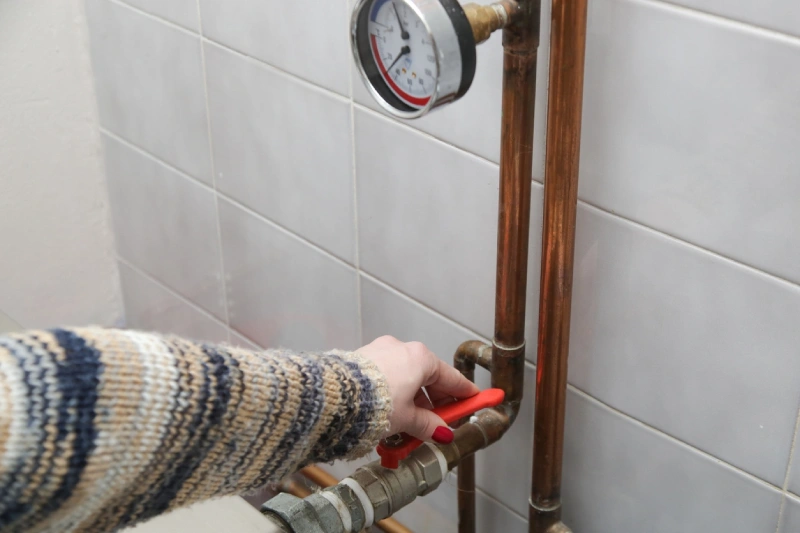 Homeowner adjusting central heating valve to keep warm during the colder months. | Mr. Rooter Plumbing of South Jersey